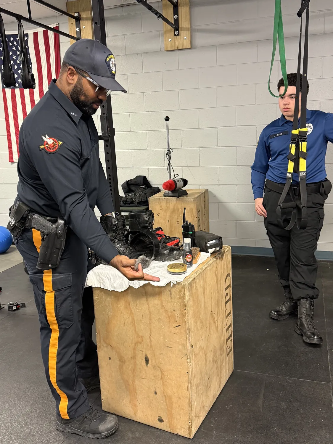 An officer teaching a cadet how to polish boots and keep their uniform to standard