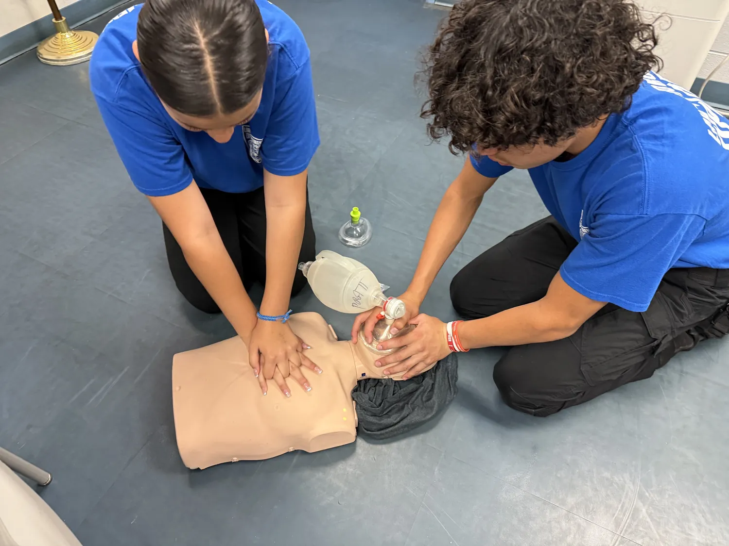 Two cadets performing CPR with a bag-valve mask on a training manikin