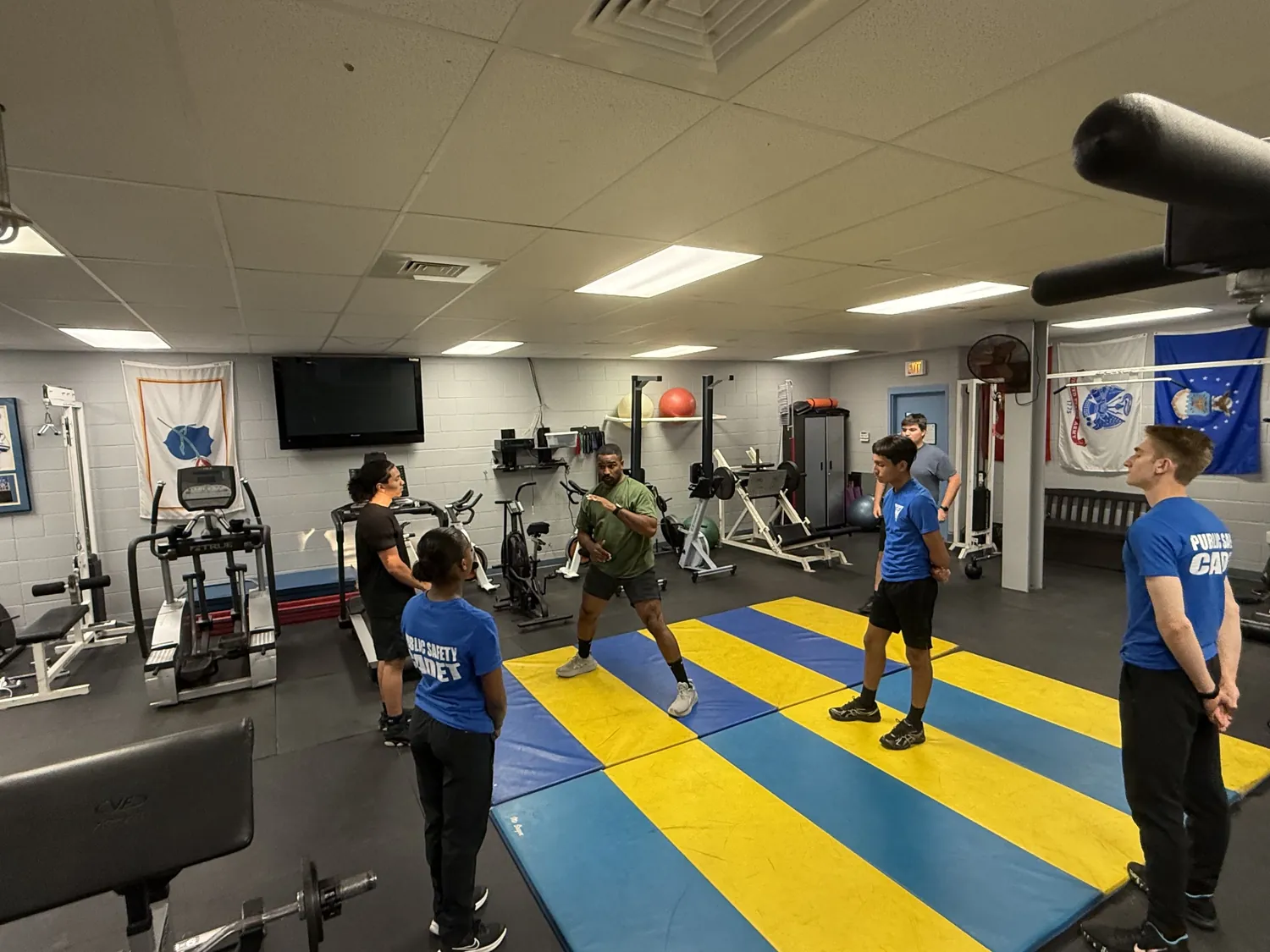 An instructor leading cadets through a physical fitness session in the gym